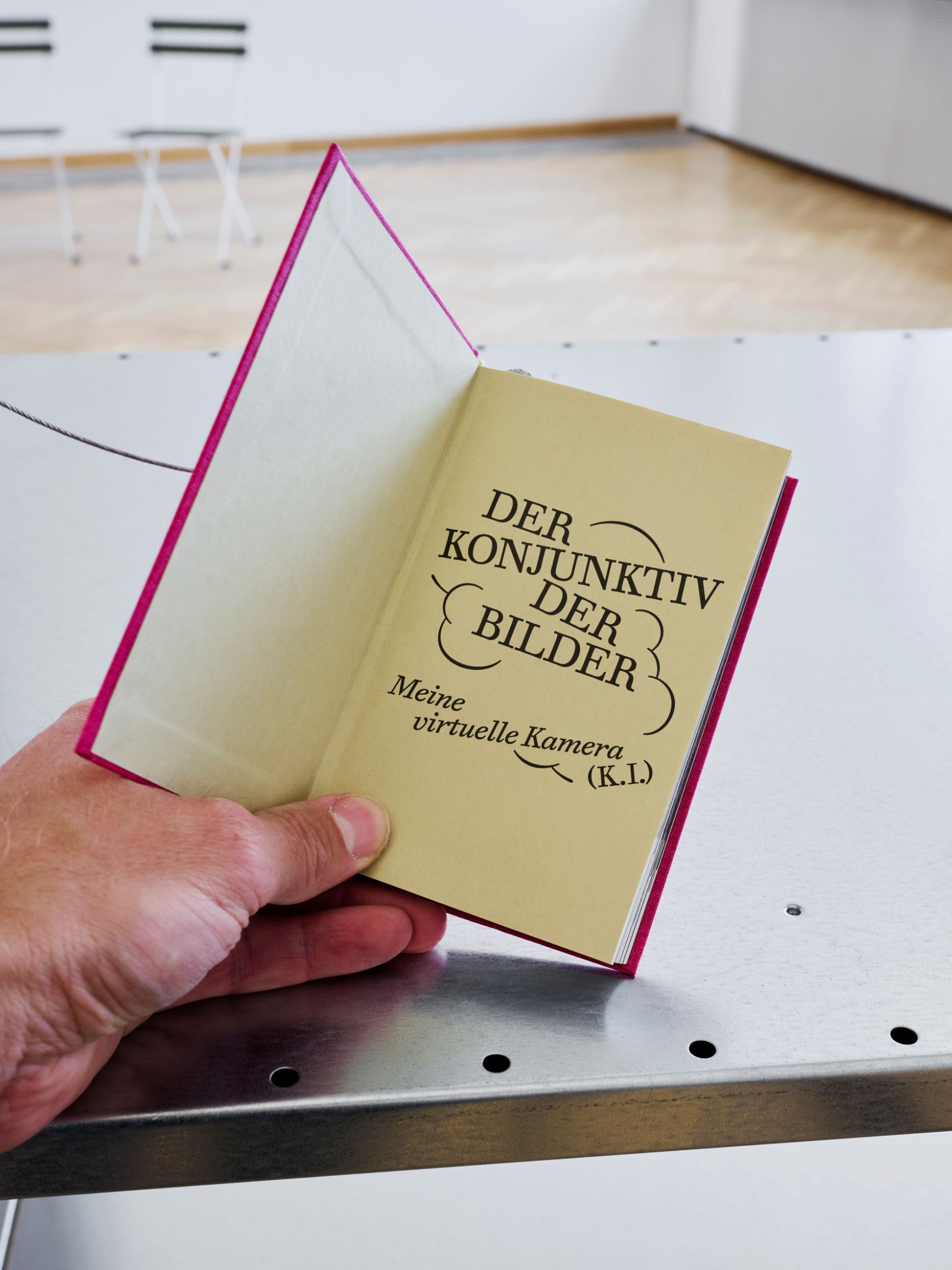 hand-mit-Buchtitel-der-konjunktiv-der-bilder-in-Alexander-Kluge-Installation-in-Austellung-Onside-Offside-Rathausgalerie